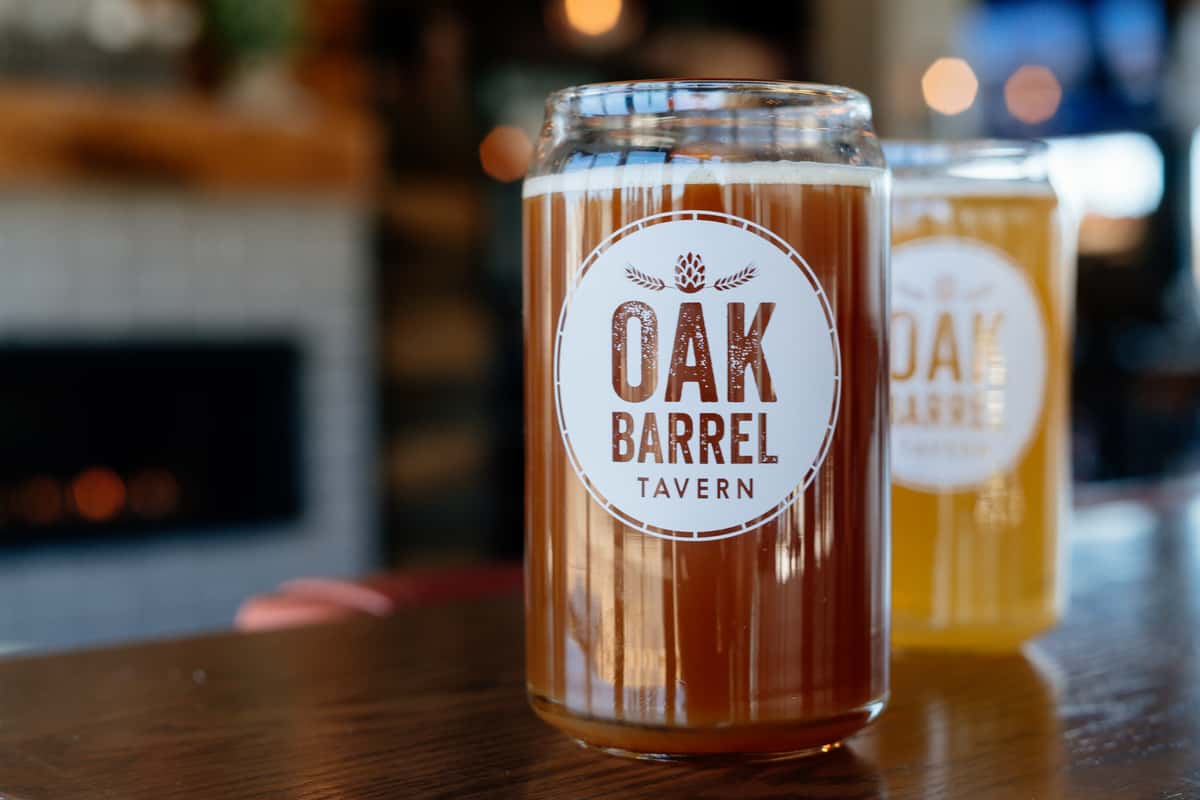 Glass of beer with the Oak Barrel Tavern logo on it