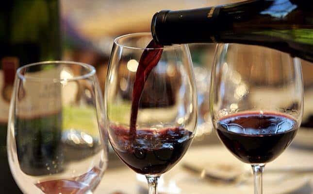 red wine being poured into 3 glasses