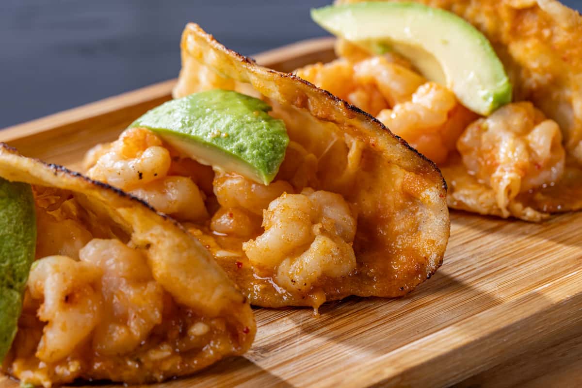 Tacosfilled with shrimp and cheese topped with sliced avocado