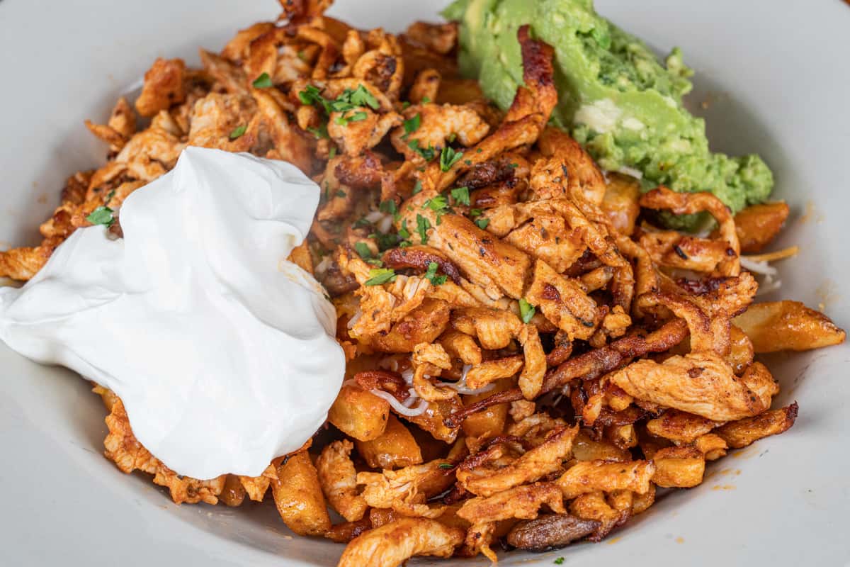 Loaded chicken fajita fries topped with seasoned chicken, guacamole, and sour cream.