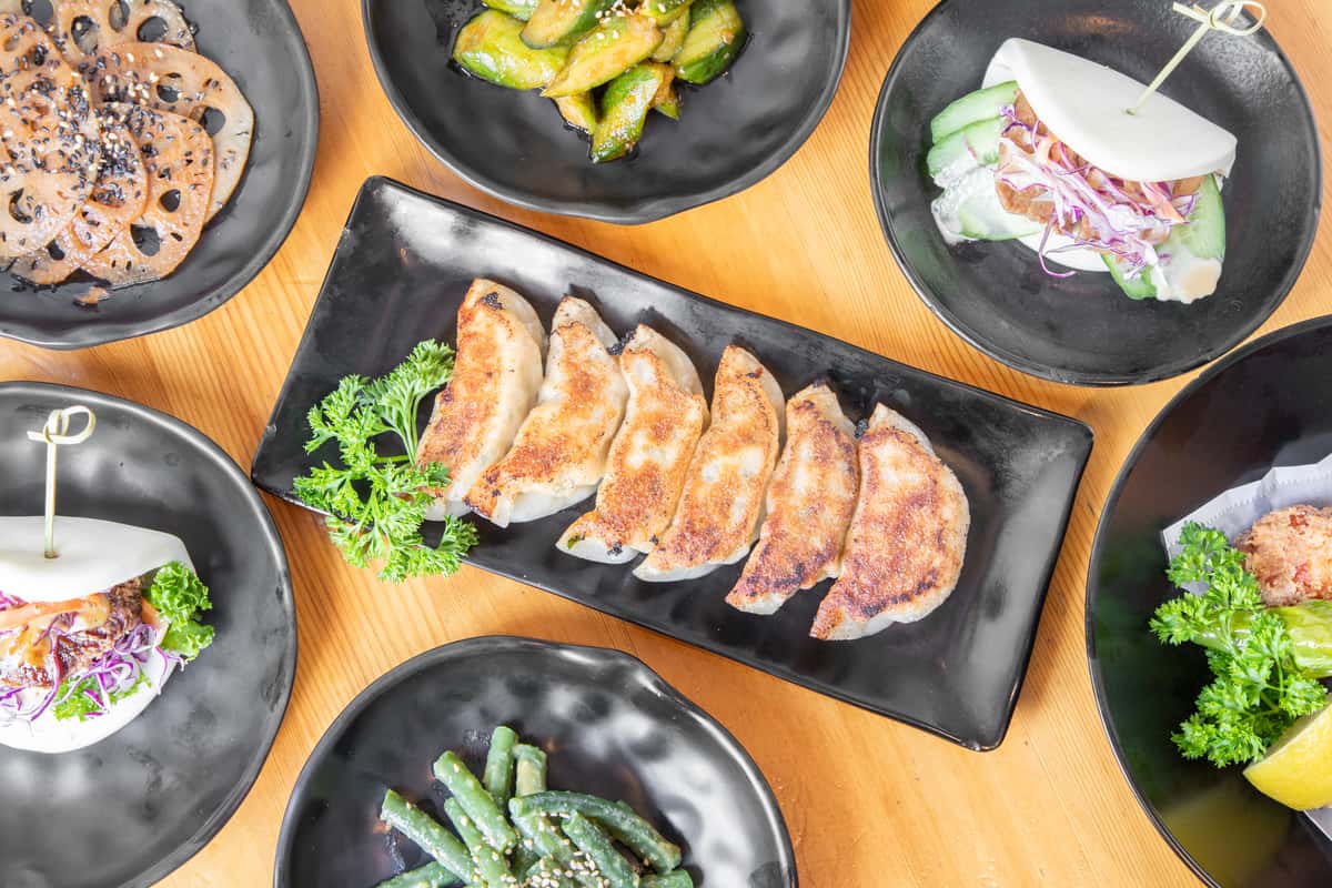 A variety of dishes on a table including dumplings, beans and steamed buns
