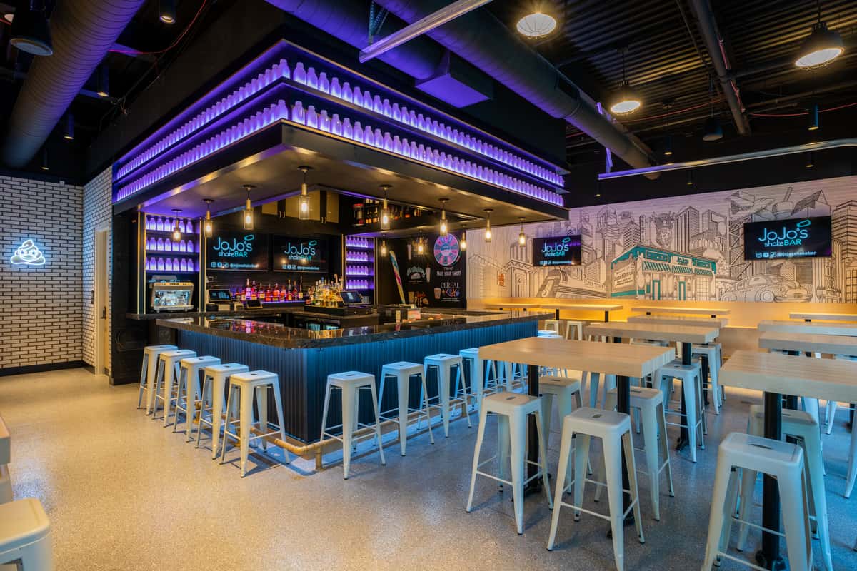 The main bar at JoJo's shakeBAR in Detroit is an intimate space lined with illuminated milk bottles, murals of iconic Detroit, high top seating, and a private full service bar