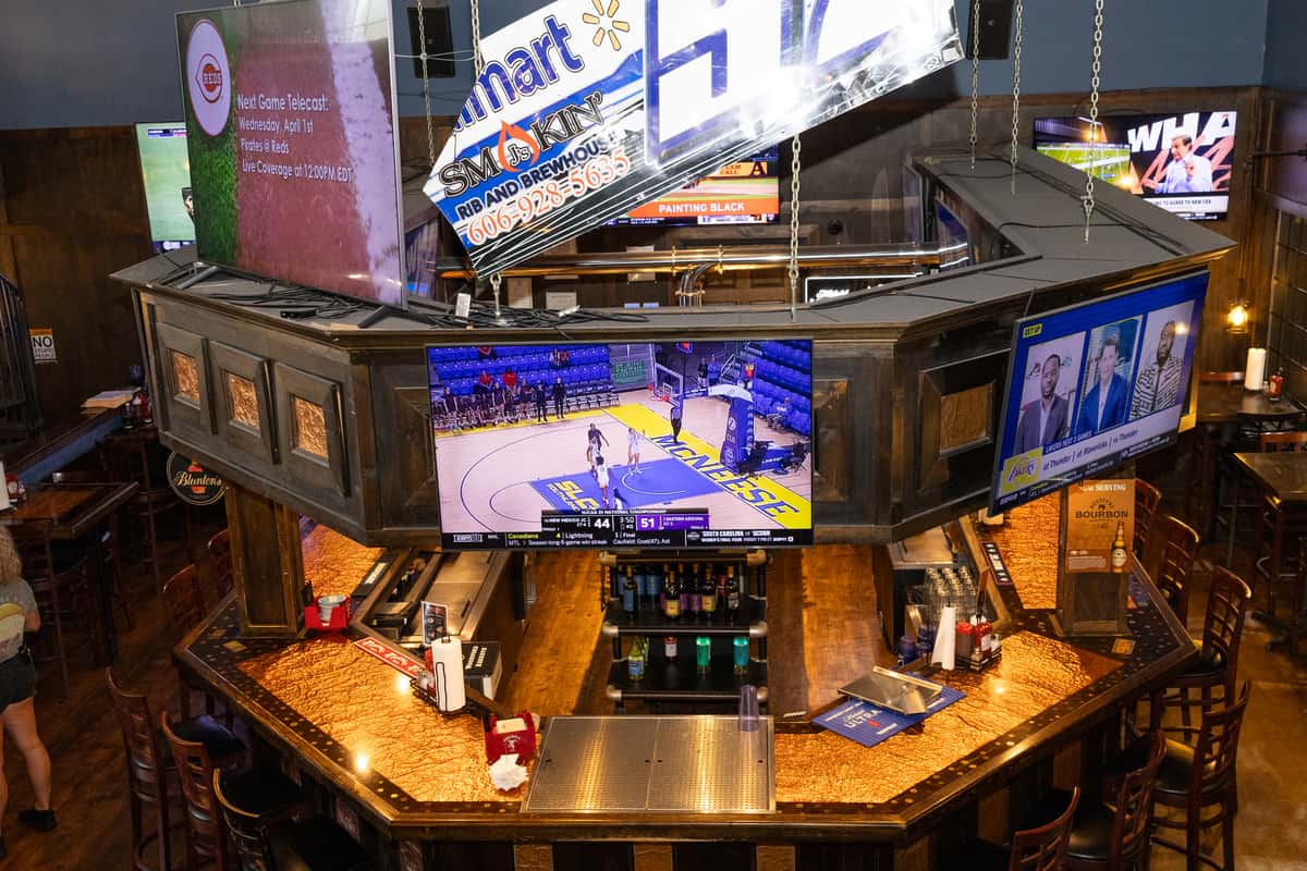 Sports bar interior with a central bar, multiple TVs showing games, and a lively casual dining atmosphere