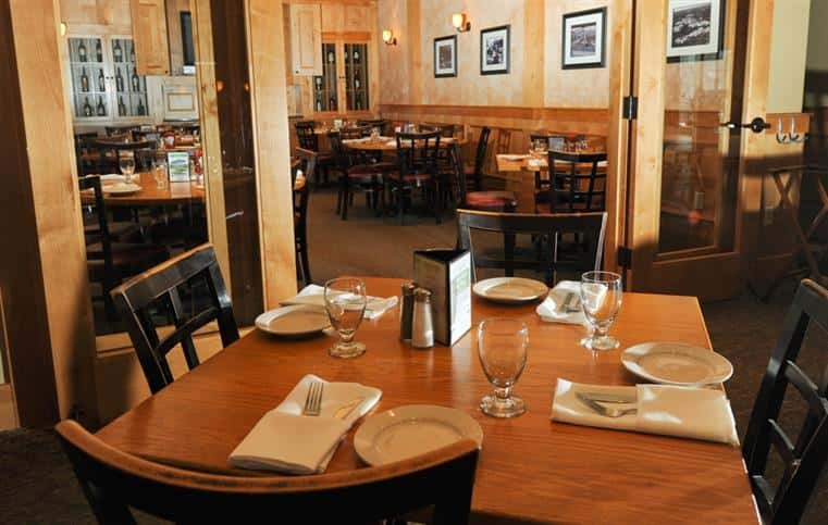 tables in the dining room setup with plates, glassware and utensils
