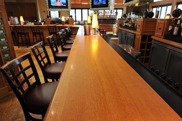 wood bartop with bar chairs lined up