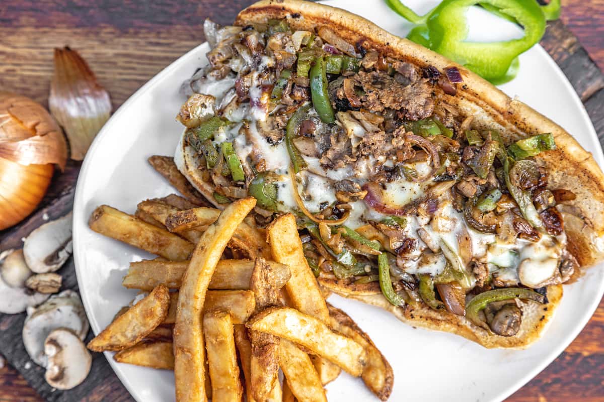 A classic Philly cheesesteak sandwich and fries on a plate