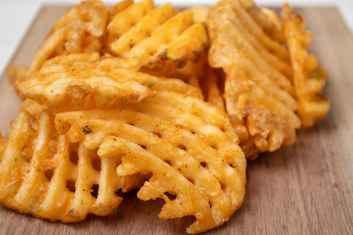 Macro shot of waffle fries on a wooden board