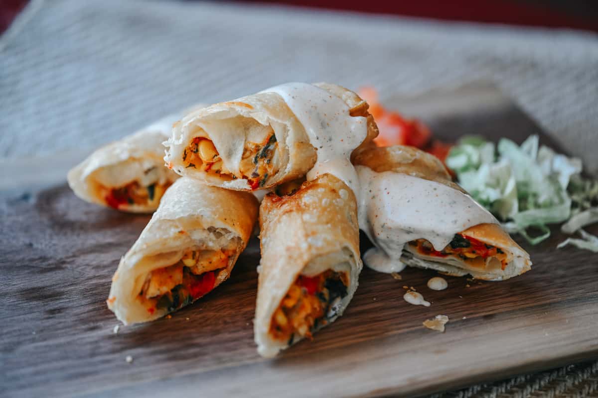 Crispy Southwest egg rolls sliced in half to reveal a savory filling of chicken, peppers, and melted cheese.