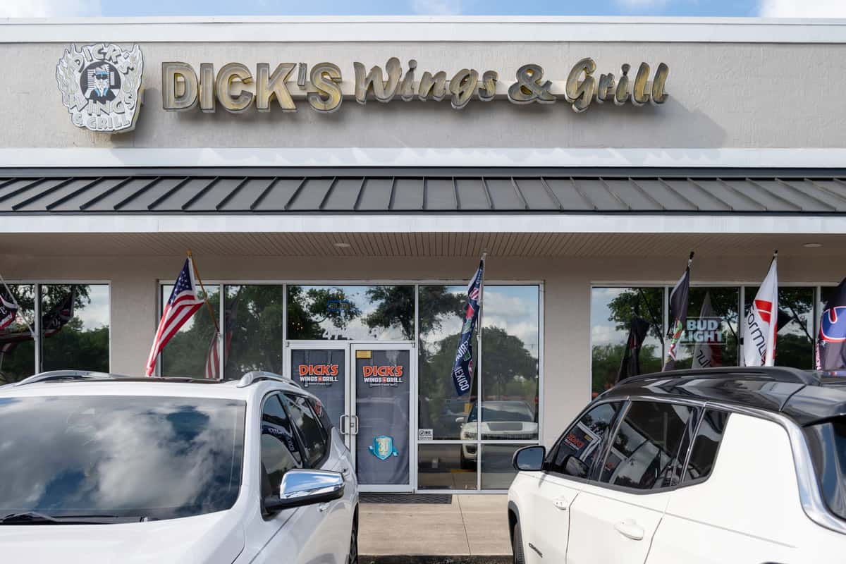 Dick's Wings & Grill restaurant storefront with branded signage, welcoming entrance, and convenient parking in front of the restaurant.