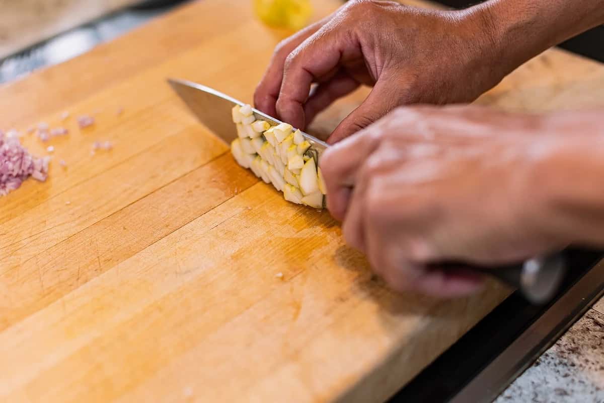 Cooking class student chopping on wooden cutting board