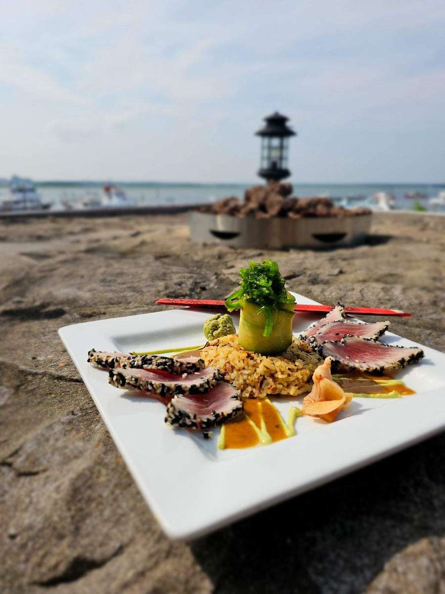 appetizer on sand with backdrop of beach, water, and lantern