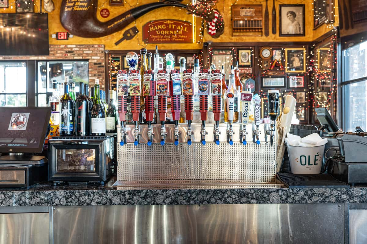 restaurant bar featuring a large tap beer wall, illuminated liquor shelves, and vintage-style decor