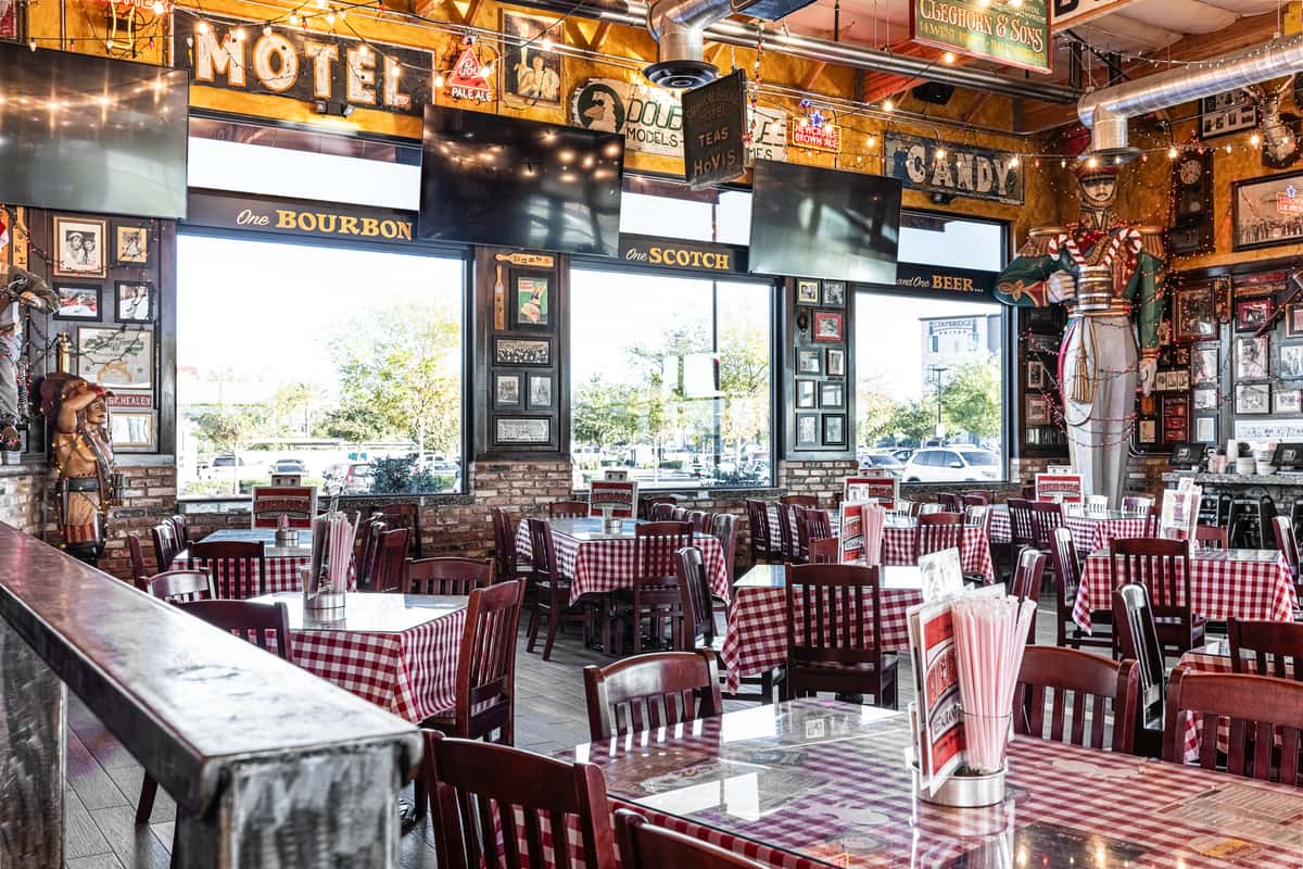 bright restaurant dining area with checkered tablecloths, large windows, and rustic wood decor
