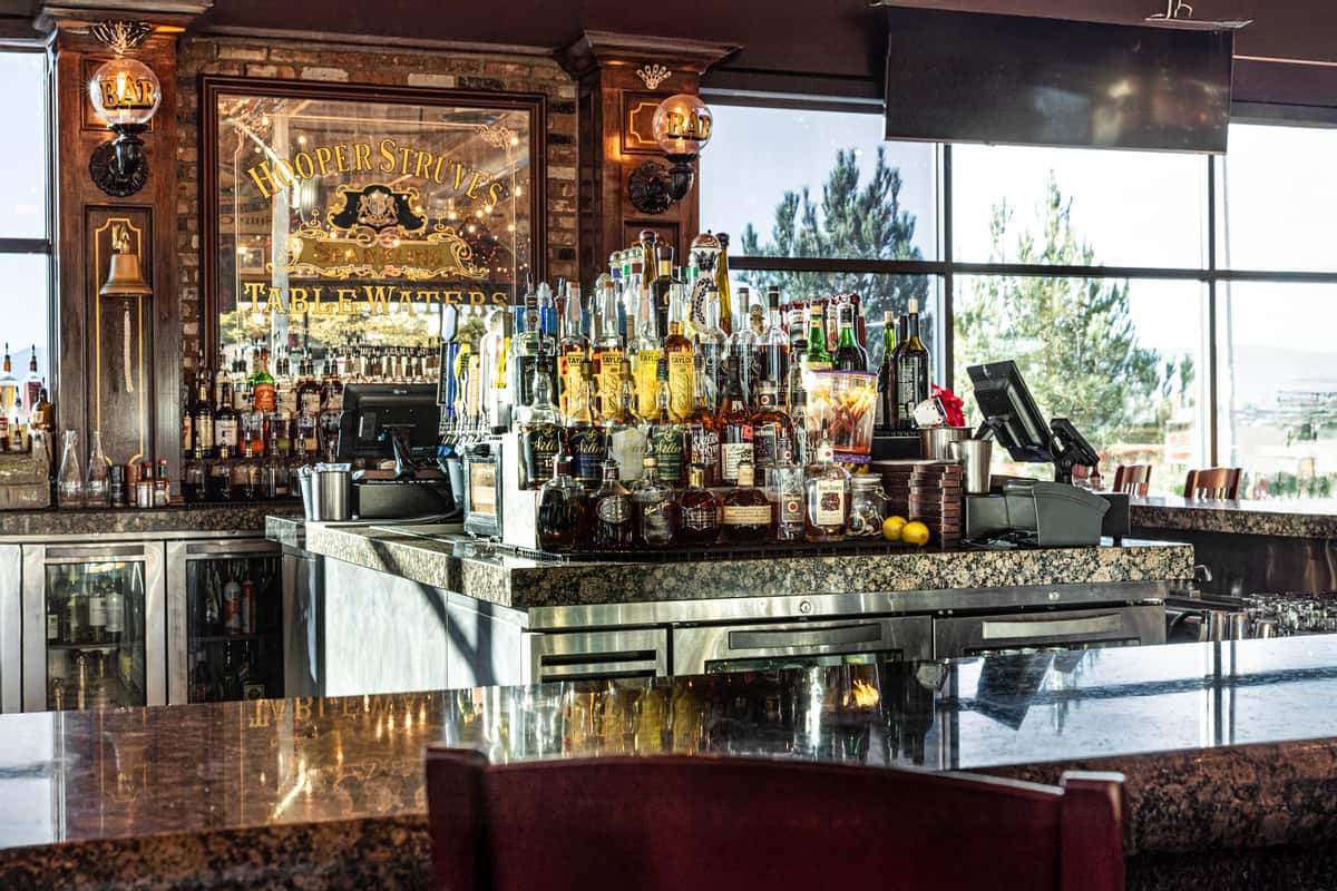 upscale restaurant bar interior with illuminated liquor shelves, mirrored accents, and elegant lounge seating