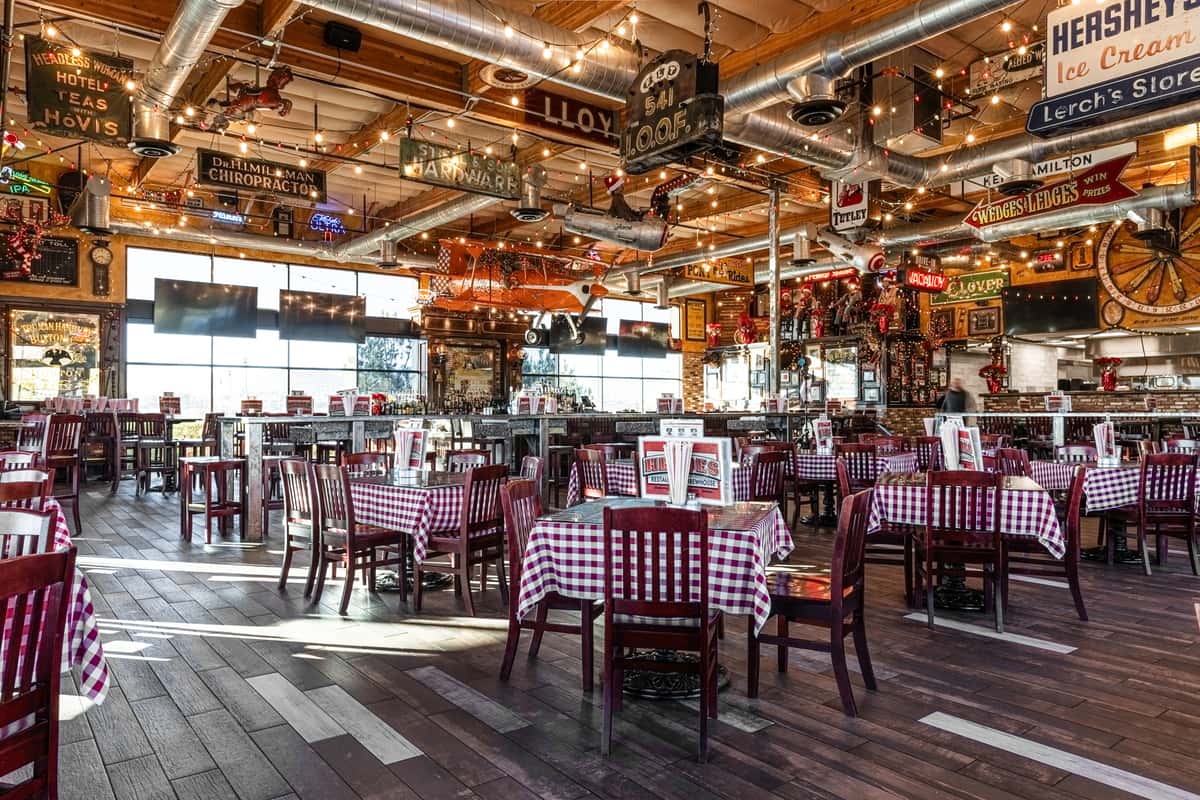 rustic restaurant dining room with checkered tablecloths, warm string lights, and spacious casual seating