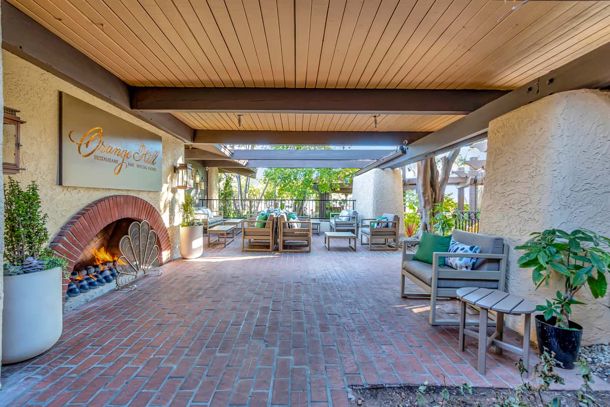 Outdoor fireplace, patio seating, and dining surrounded by red brick.