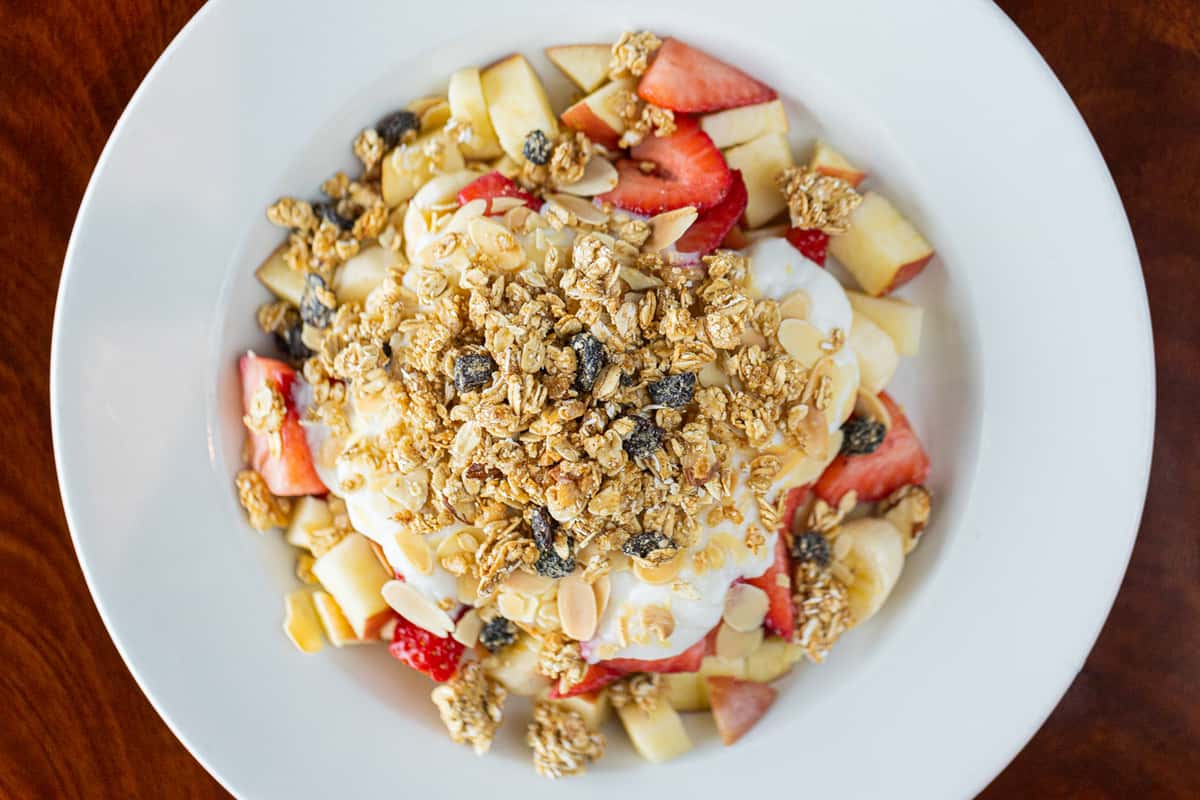 granola bowl with yogurt, strawberries, apples, and blueberries
