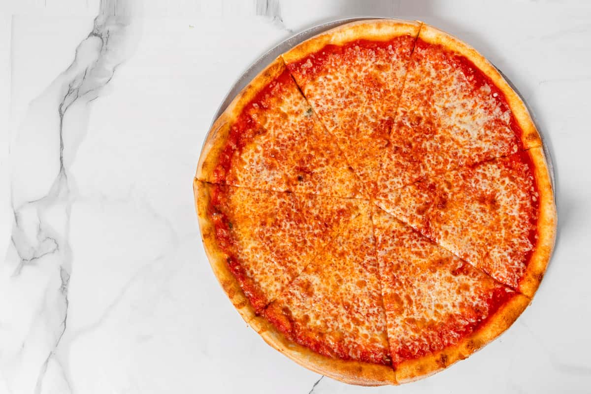 Classic New York style cheese pizza with melted mozzarella and rich tomato sauce on a thin, golden crust, sliced into eight pieces