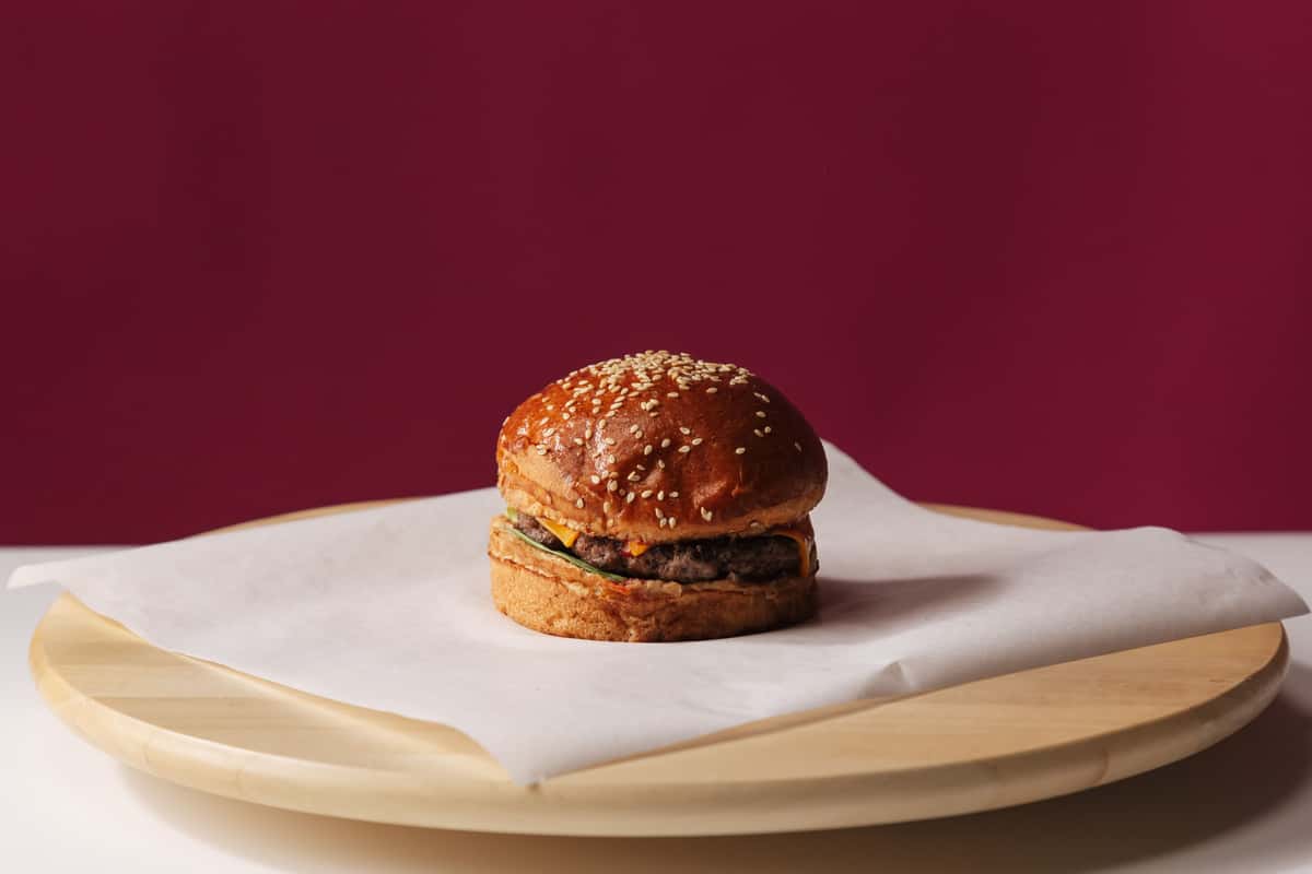 mouth-watering-hamburger-with-sesame-bun-on-wooden-plate-per