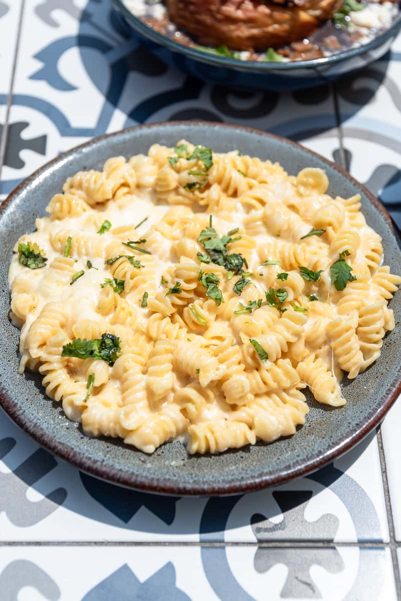 Creamy rotini mac and cheese topped with fresh herbs, served in a rustic ceramic bowl—comfort food favorite ideal for brunch, kids' menus, or indulgent side dish offerings.