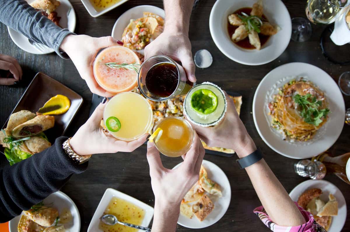 friends toasting cocktails over delicious meal