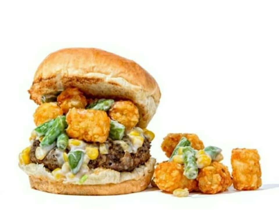 Burger topped with creamed asparagus, corn and tater tots