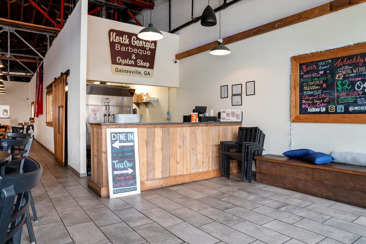 Interior of North Georgia BBQ restaurant showing the counter area with wood panels, tile flooring, and the restaurant's sign on the wall