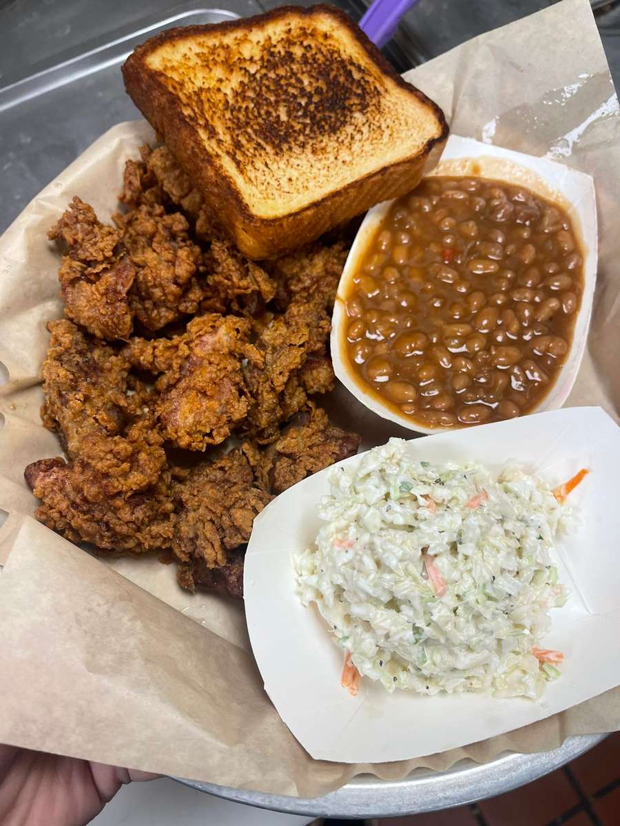 Southern-style fried chicken platter with crispy golden chicken, baked beans, creamy coleslaw, and toasted bread on a metal tray