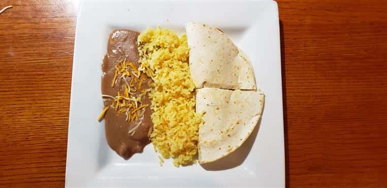 quesadilla with rice and refried beans on a white plate
