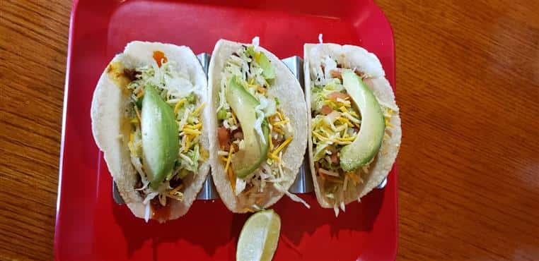 three tacos topped with cheese and avocado