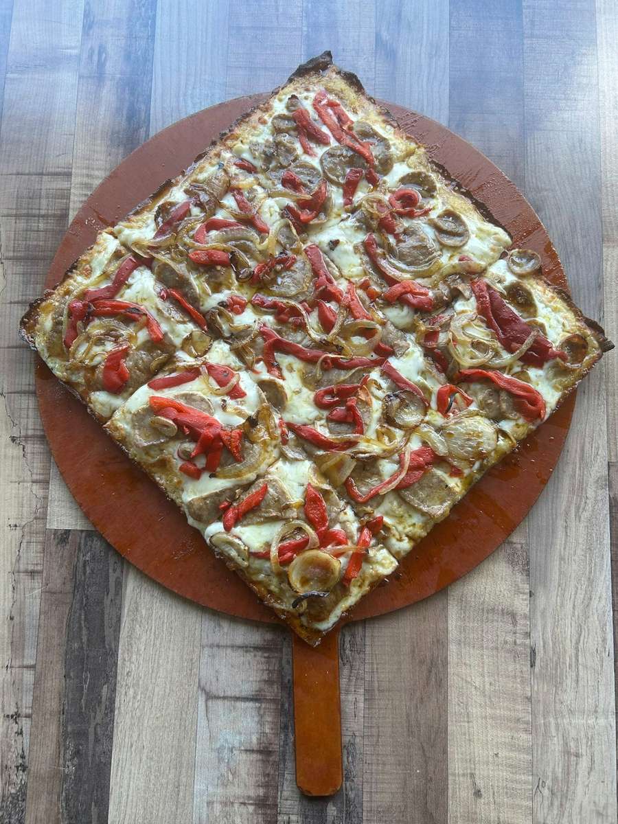 Square pizza topped with sliced sausage, roasted red peppers, and caramelized onions on a golden, crispy crust.