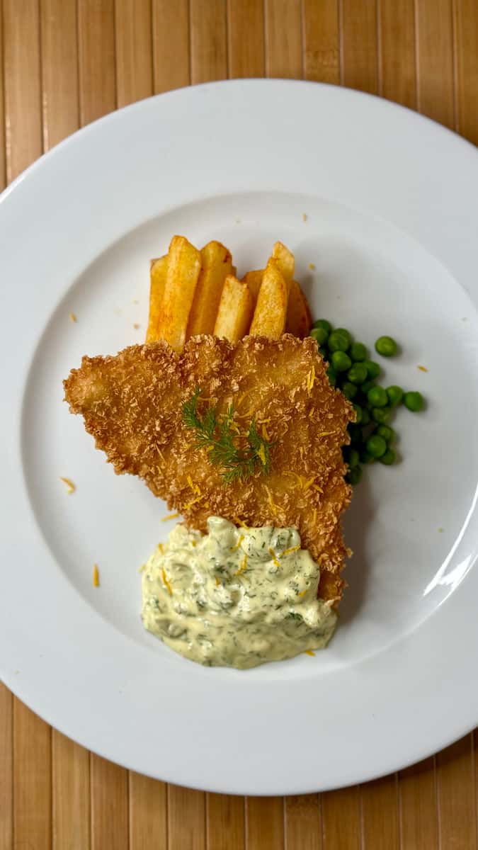 Crispy breaded fish served with golden chips, green peas and a creamy traditional side.