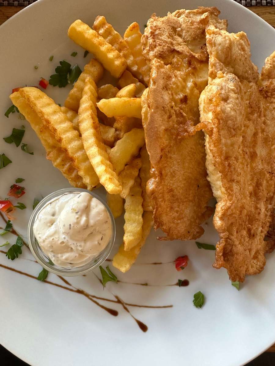 Freshly cooked battered fish served with golden crinkle-cut chips and a creamy dipping sauce.