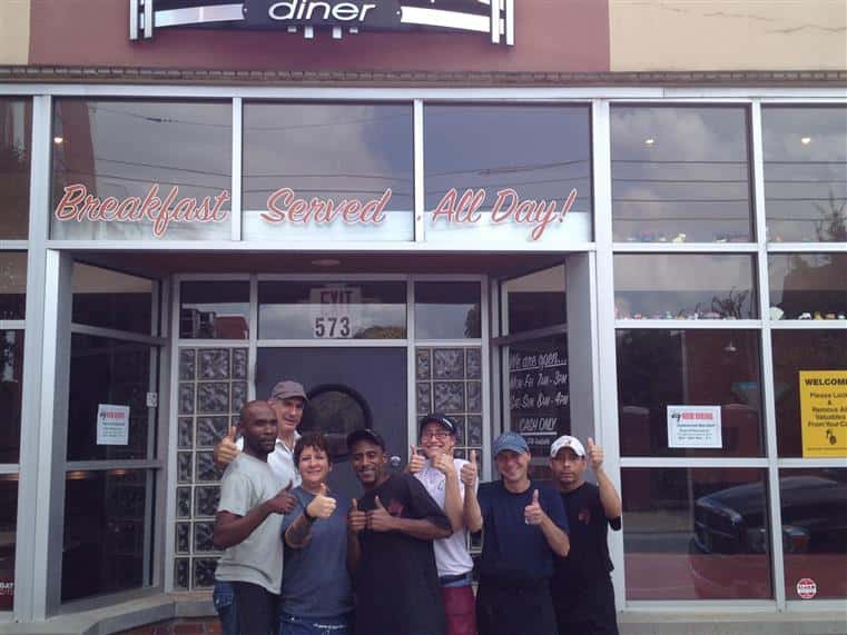 six staff members holding their thumbs up outside the front of thumbs up diner 
