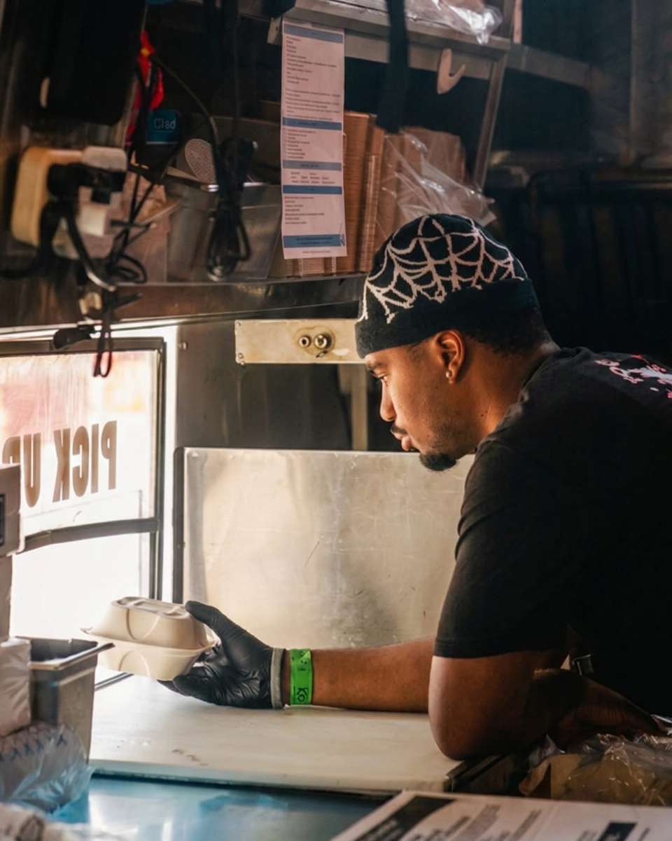 A person in a cap and glasses looking down at a counter