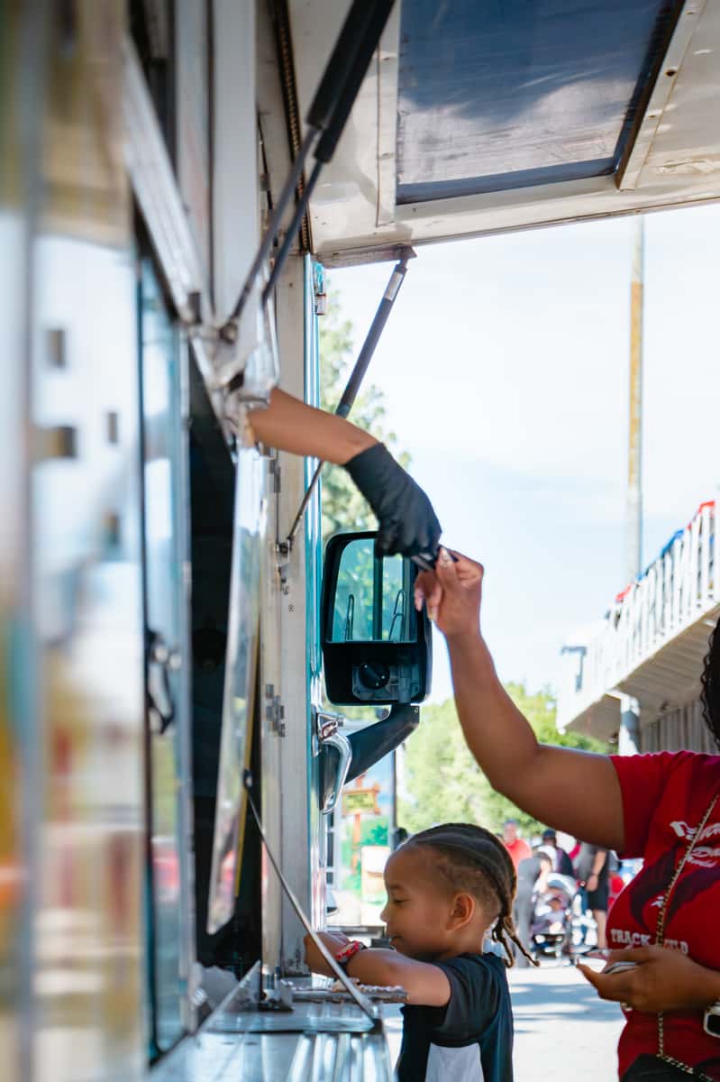HOA event catering in Los Angeles: a resident picking up loaded fries at the FryDay Food Truck window