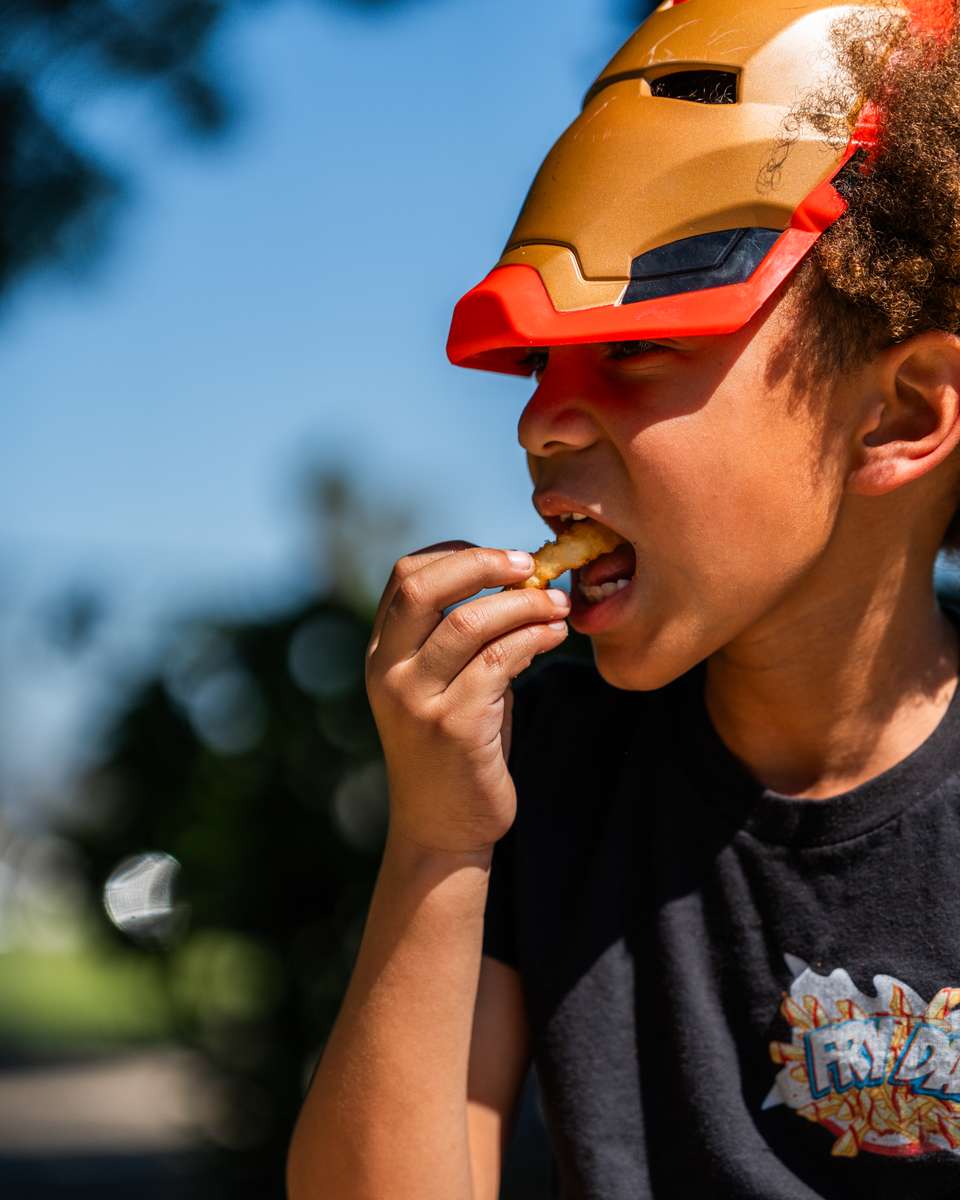 Child eating FryDay loaded fries at an outdoor fall festival in Los Angeles