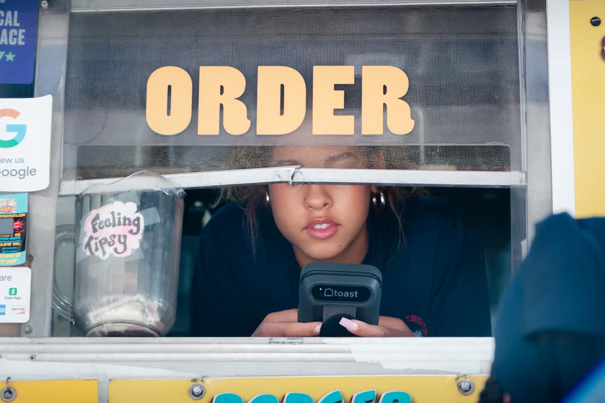 Food truck franchise technology in action: a FryDay crew member running the point-of-sale system at the order window in Los Angeles