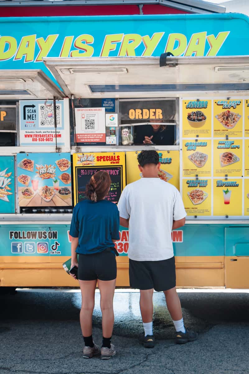 Oktoberfest catering in Los Angeles: guests ordering loaded fries at the FryDay Food Truck at an outdoor fall party