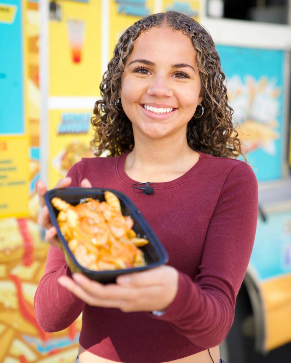 Smiling guest holding FryDay loaded fries at a senior living community event in Los Angeles