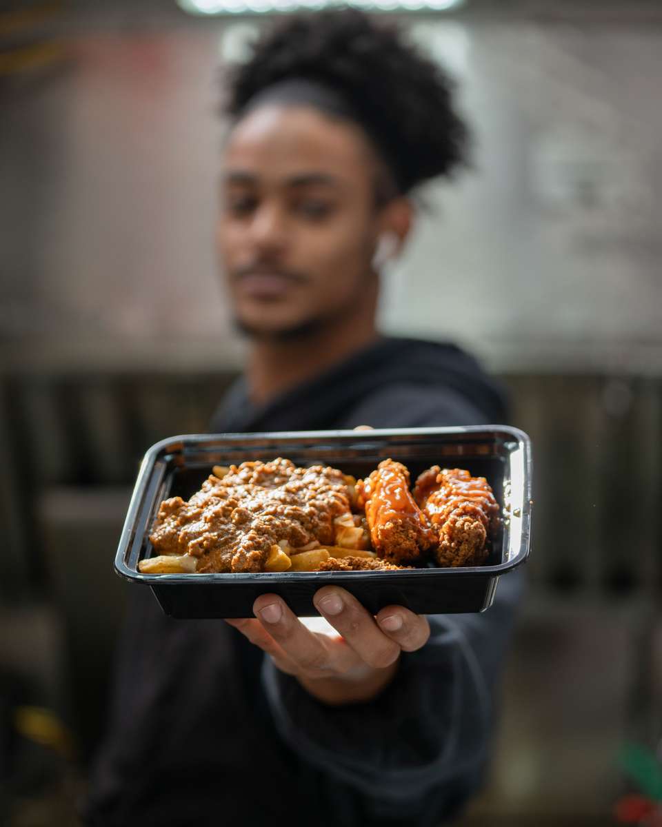 A FryDay team member holding a tray of freshly made loaded fries in Los Angeles