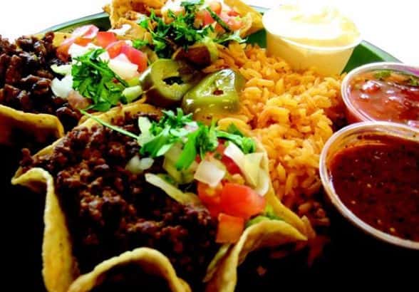 Taco salad with yellow rice, parsley, tomatoes, jalapenos, and dipping sauces