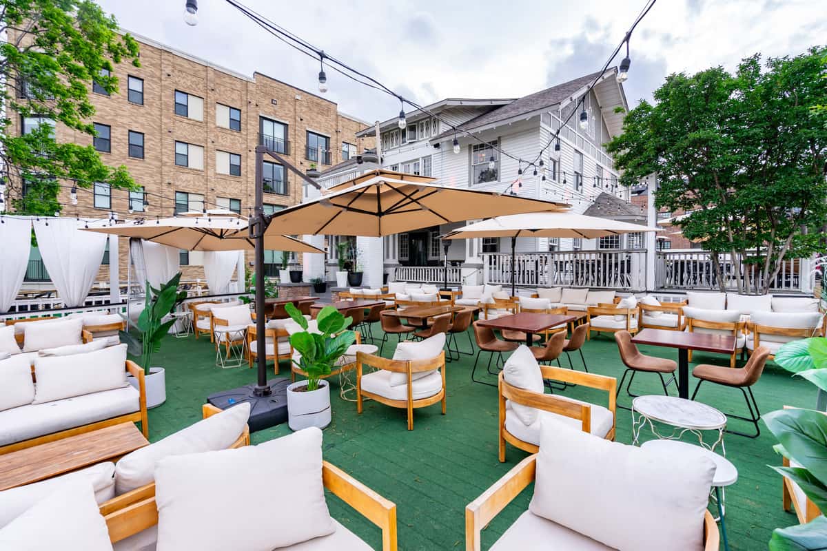 Charming outdoor patio of Selda Mediterranean Grill, featuring wooden furniture and umbrellas, lush greenery, and a relaxed atmosphere for al fresco dining.