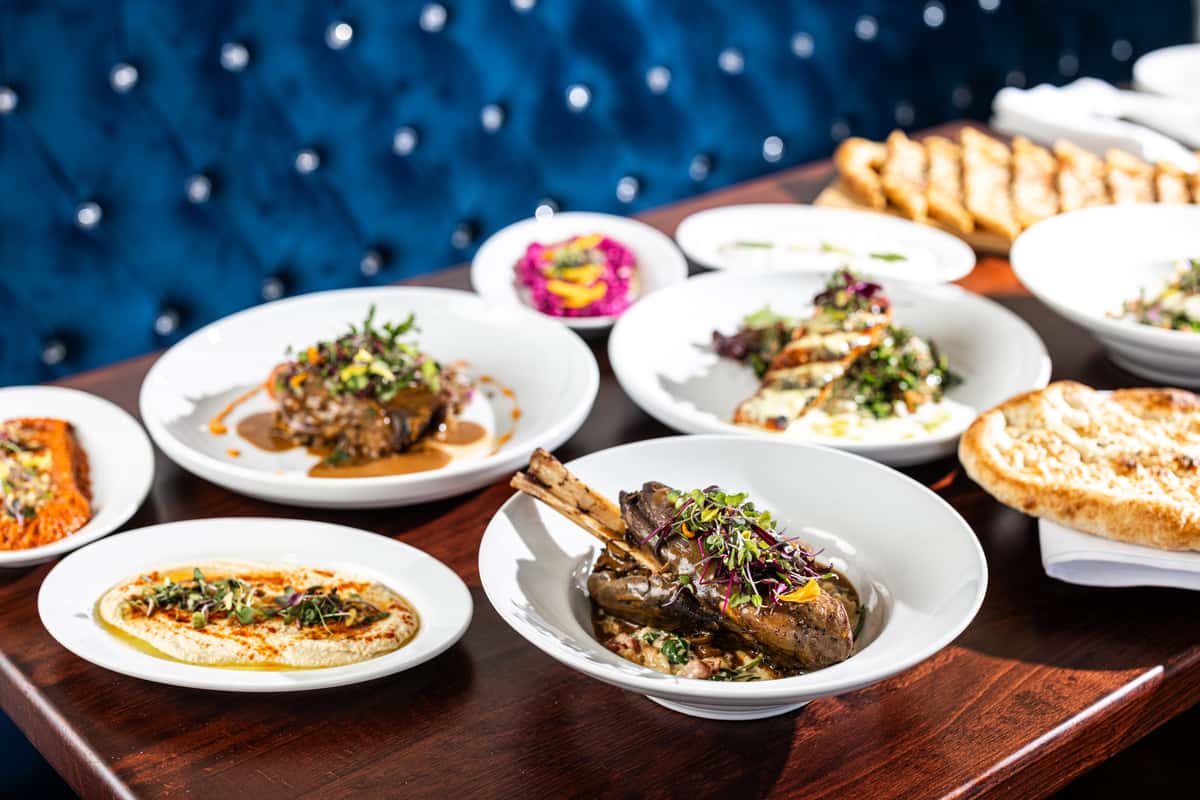 Assorted Mediterranean dishes from Selda Mediterranean Grill, featuring tender lamb, vibrant dips, and fresh salads, beautifully presented on a warm wooden table.