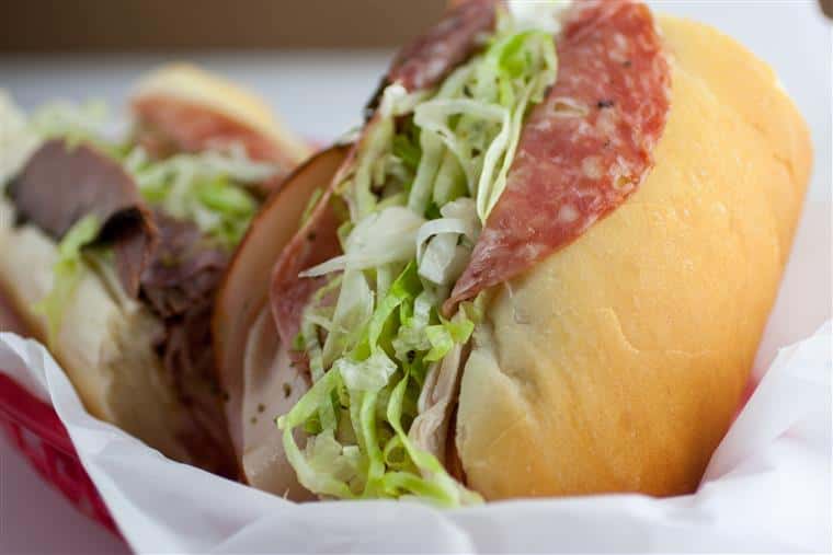 A sub with lettuce, salami, roast beef and turkey