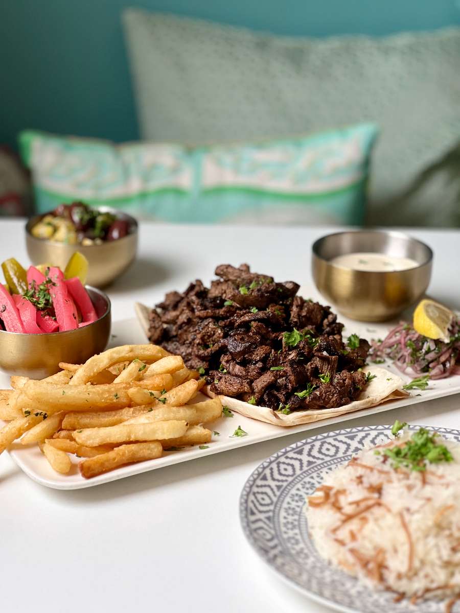 Charcoal-grilled Lebanese beef shawarma served with crispy fries, house pickles, garlic sauce, and warm pita at Lira House in Wynwood, Miami.