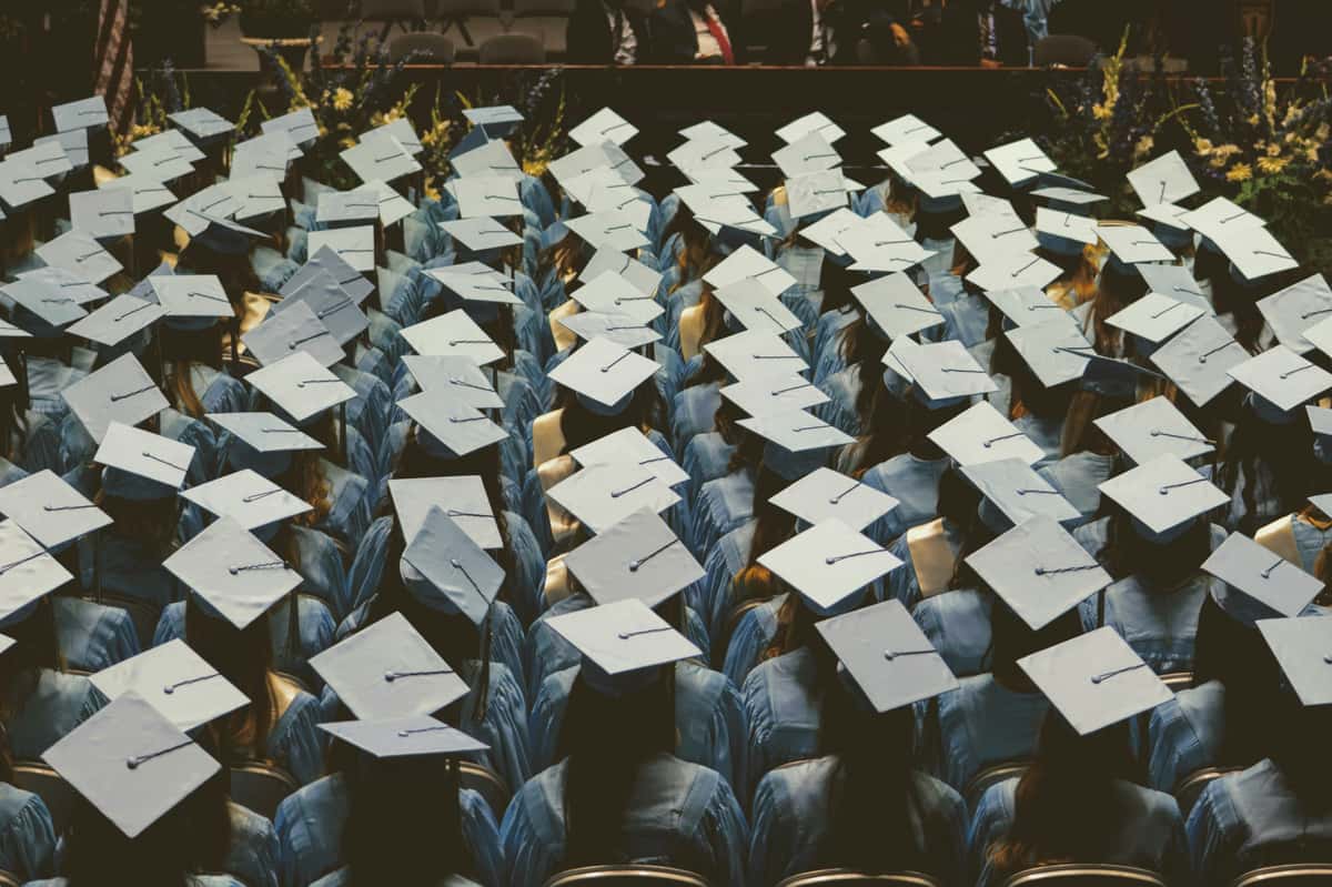 Graduates in light blue caps and gowns seated in rows during a formal commencement ceremony.