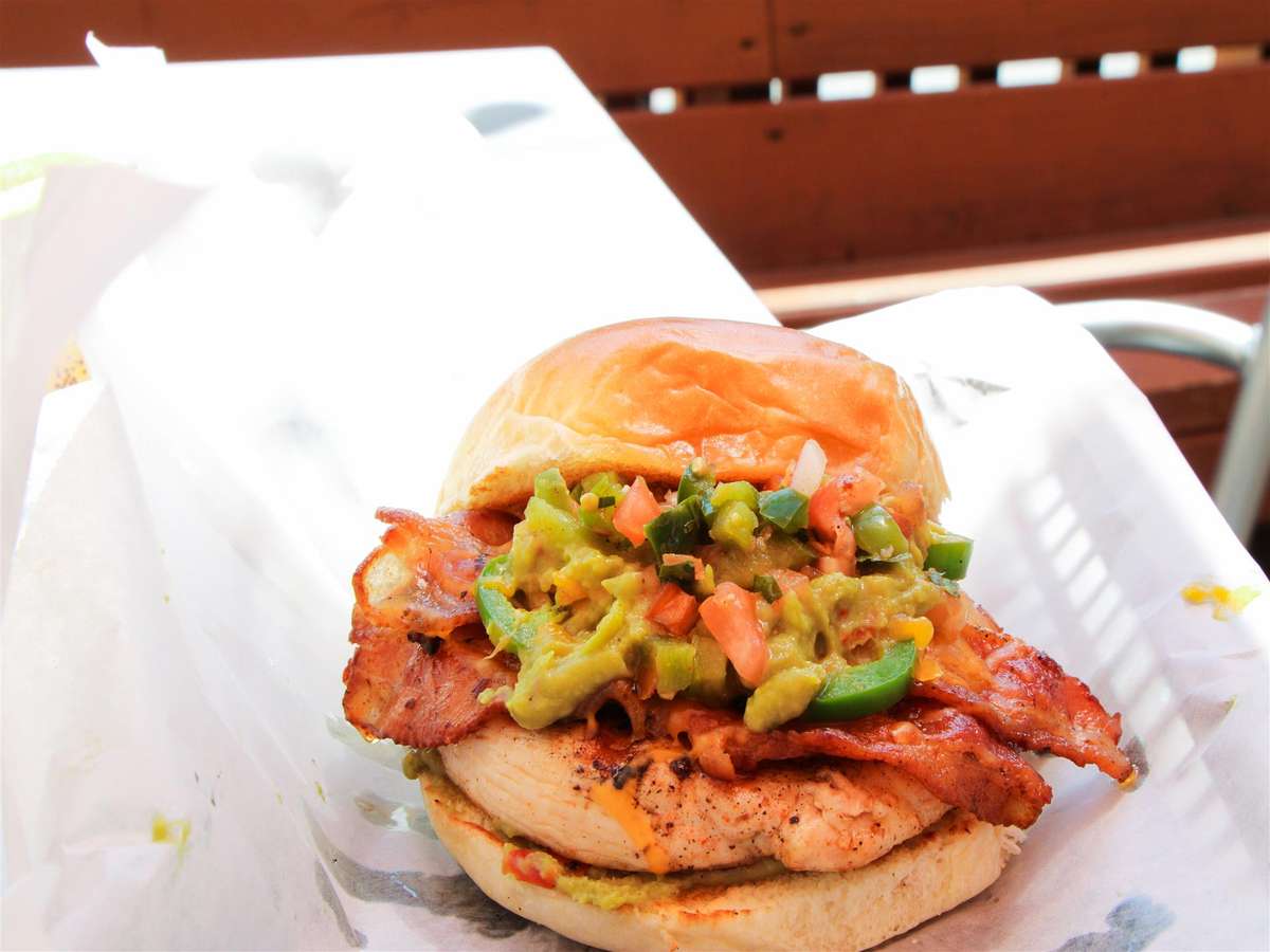 chicken sandwich topped with bacon, cheese and chopped bell peppers.