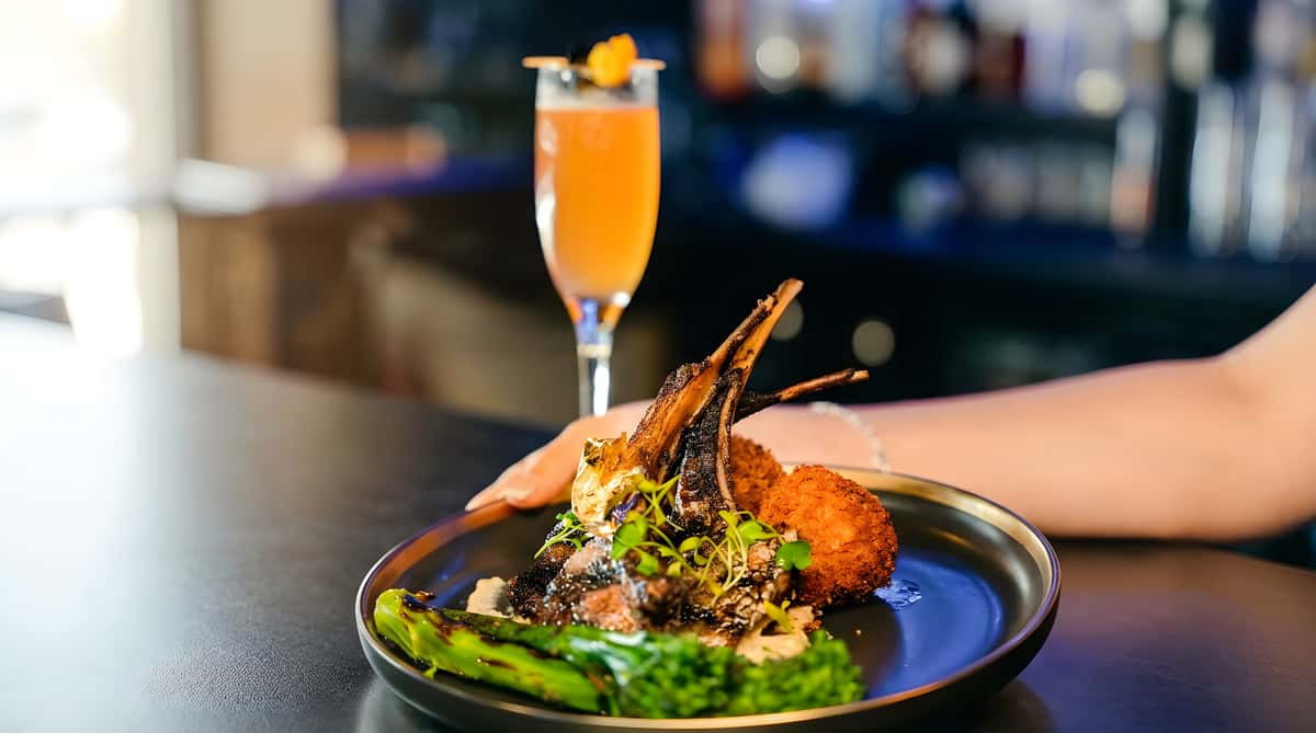 Grilled lamb chops with gold leaf, microgreens, round fried sides, and blanched broccoli.