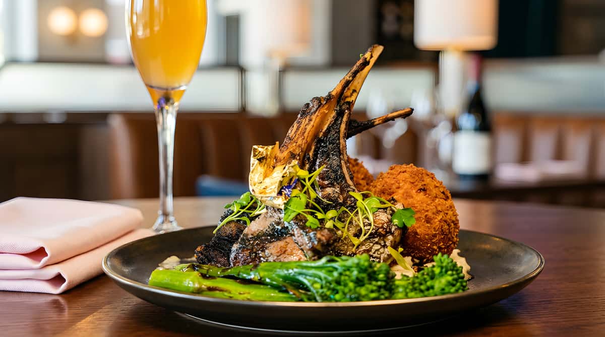 Grilled lamb chops with gold leaf, two croquettes, seasoned broccoli rabe, and an orange cocktail.